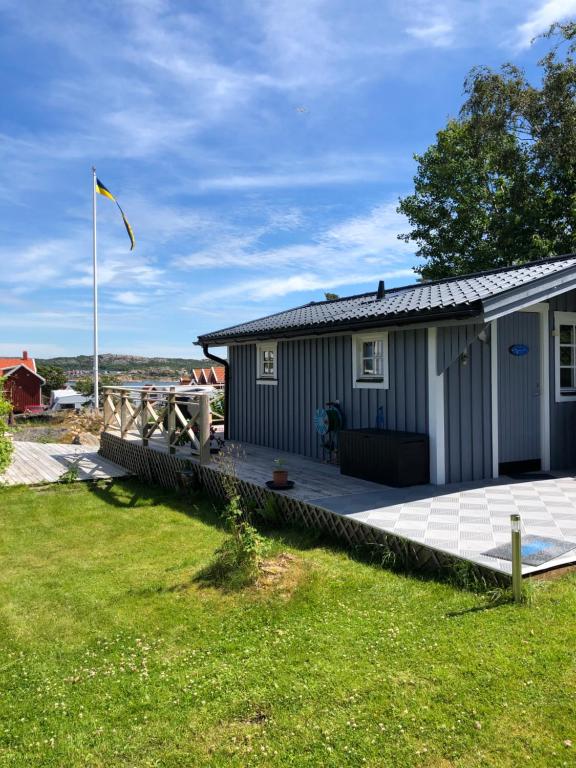 uma pequena casa com um deque e uma bandeira em Hunnebostrand, Ramsviklandet, Smögen, Bohuslän, Vestkusten em Hunnebostrand