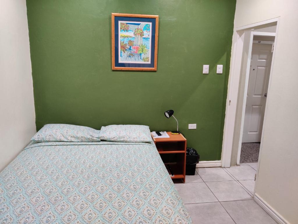 a bedroom with a bed and a table with a picture at Woodbrook on the Avenue in Port-of-Spain