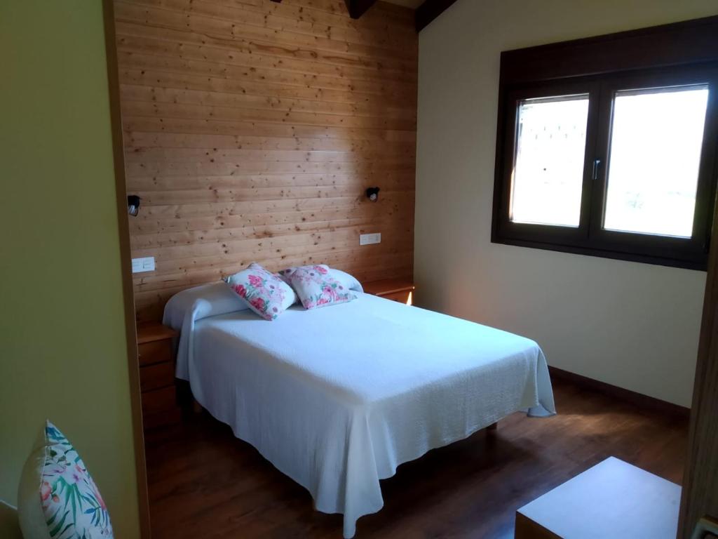 1 dormitorio con cama blanca y ventana en Apartamentos Rurales Casa Fonso, en Navia