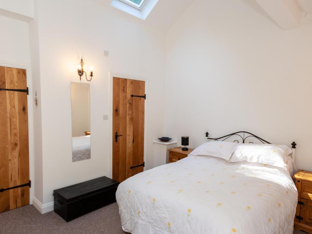 a white bedroom with a bed and a mirror at Bodafon Hall Cottages in Llandudno