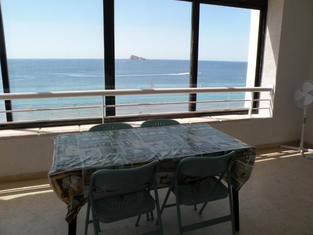 een tafel en stoelen in een kamer met uitzicht op de oceaan bij Torre Levante - Fincas Arena in Benidorm