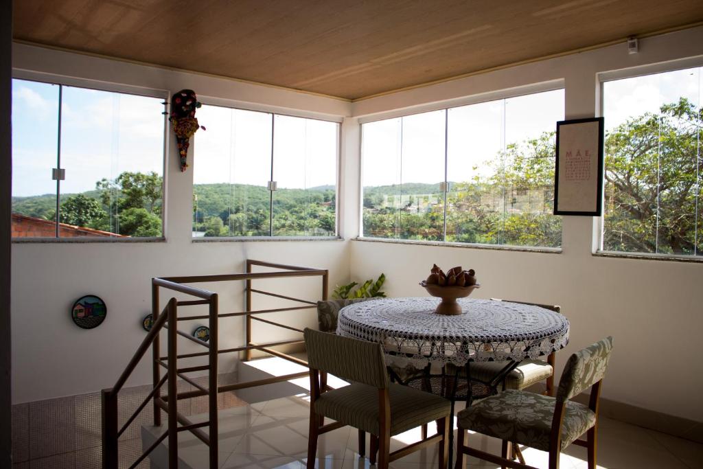 ein Esszimmer mit einem Tisch, Stühlen und Fenstern in der Unterkunft Pousada Recôncavo in São Félix