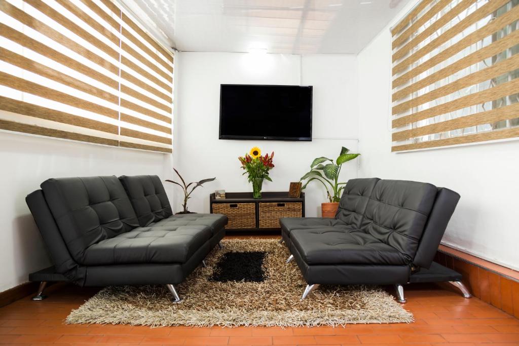 two black leather chairs in a living room with a tv at Deportel Bogotá in Bogotá