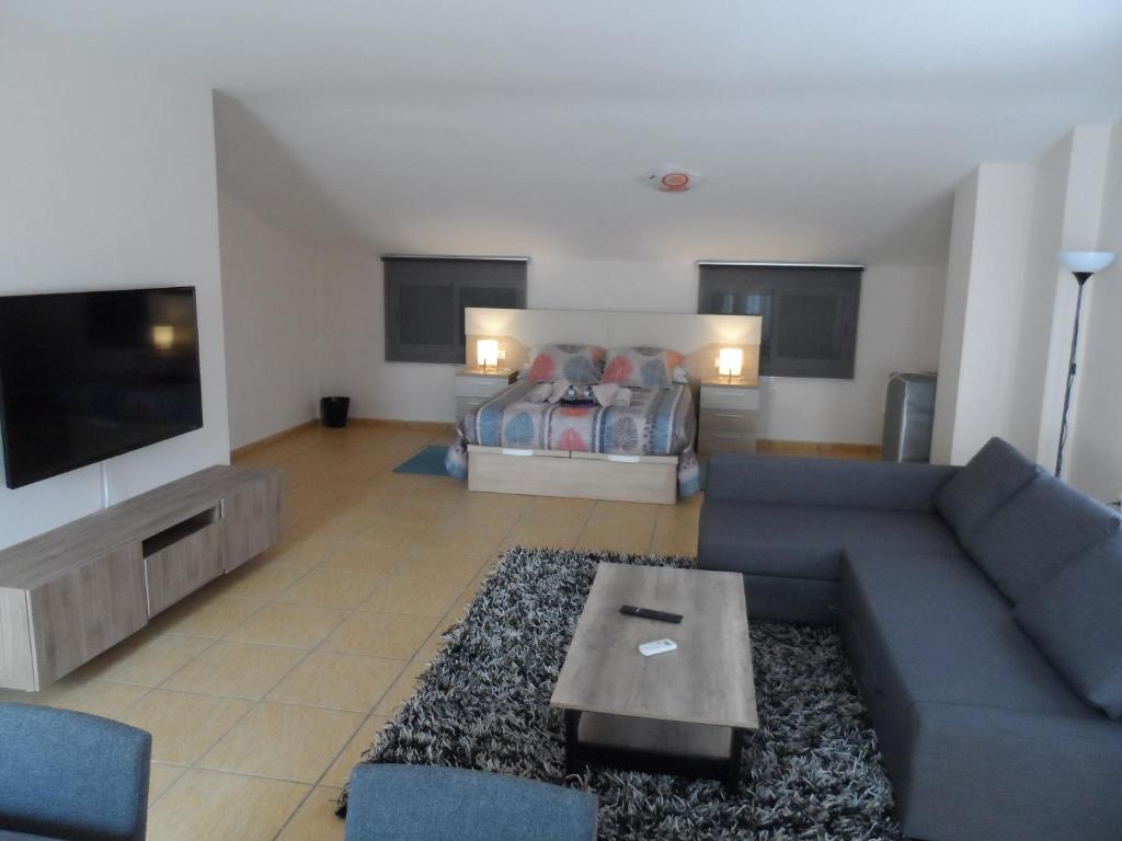 ein Wohnzimmer mit einem blauen Sofa und einem Bett in der Unterkunft CASA CLIMATIZADA VACACIONAL in Villalonga
