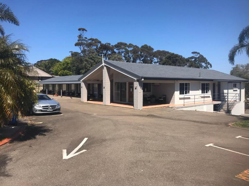 a building with a car parked in a parking lot at Breeze Inn 13 Princes Highway, Ulladulla in Ulladulla