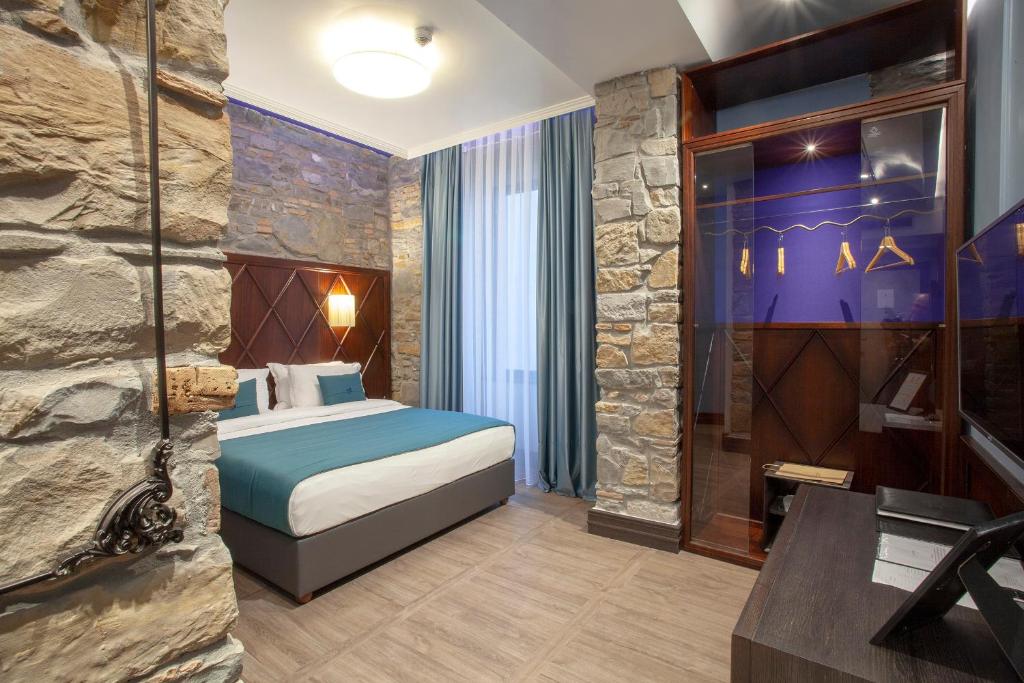 a bedroom with a bed and a stone wall at Hotel Solun in Trieste