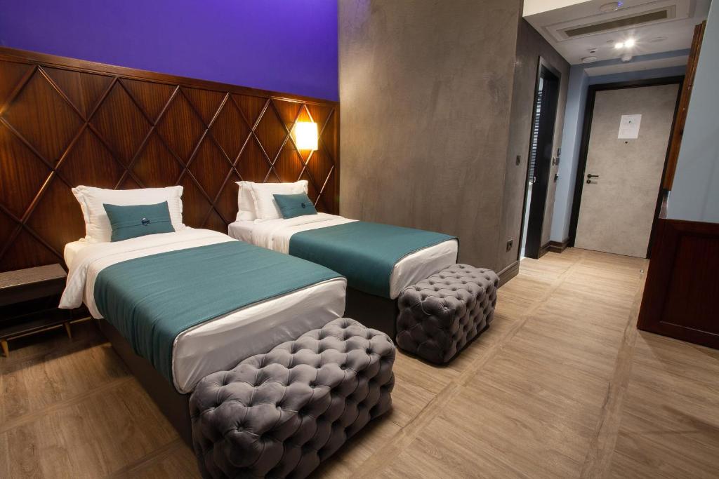 a hotel room with two beds and a stool at Hotel Solun in Trieste