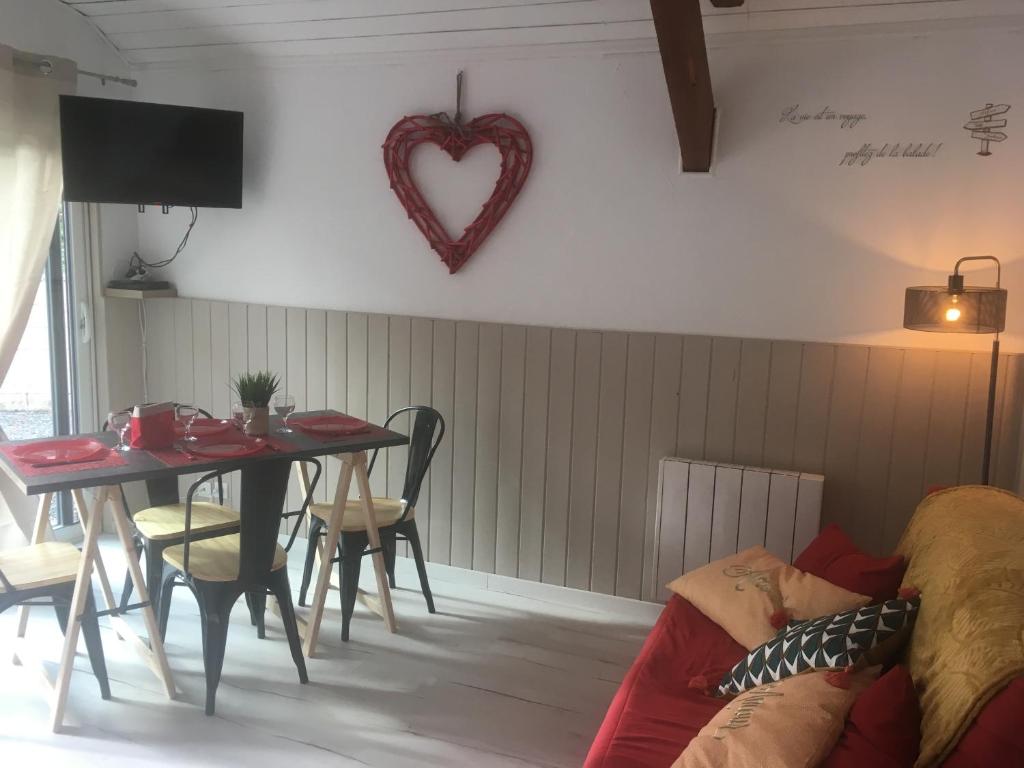 a living room with a table and a heart hanging on the wall at Appartements La Durance et L'Helpe in Embrun