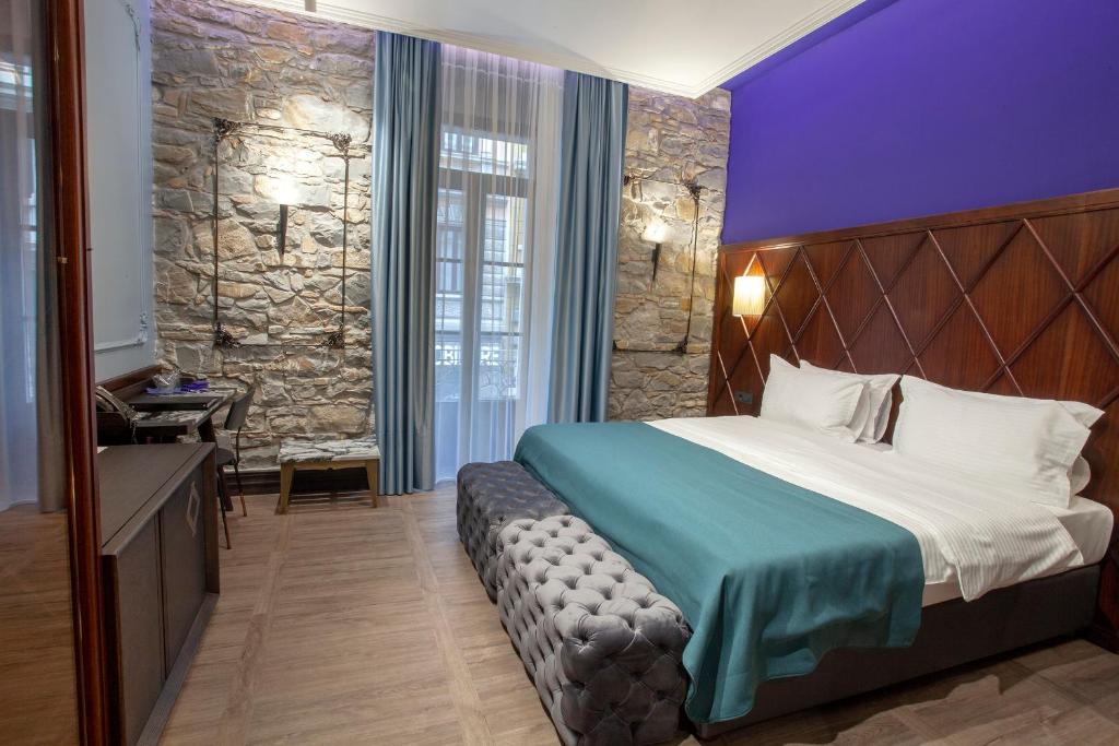 a hotel room with a bed and a stone wall at Hotel Solun in Trieste