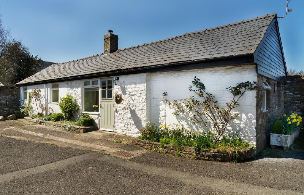 a small white cottage with a door on a street at The Neuadd Cottages in Crickhowell