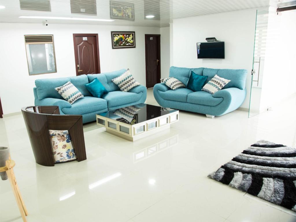 a living room with blue couches and a tv at Hotel Las Colonias in Bogotá