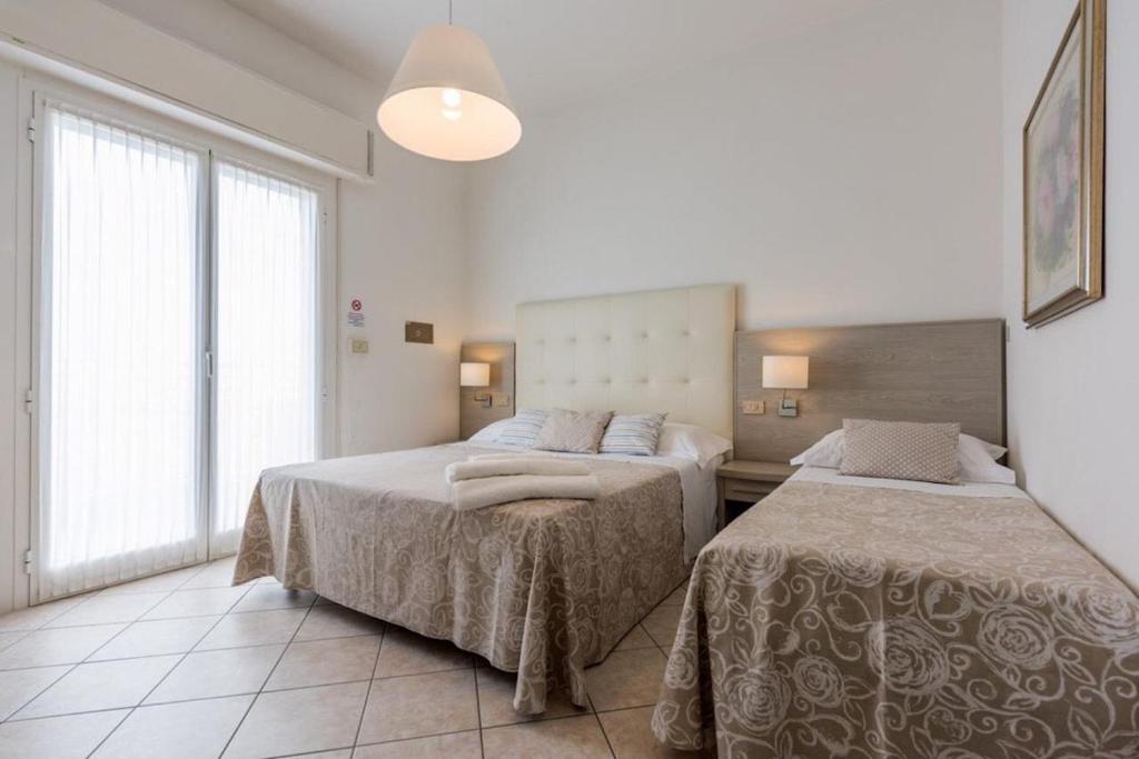 a bedroom with two beds and a large window at Hotel Alda in Cervia