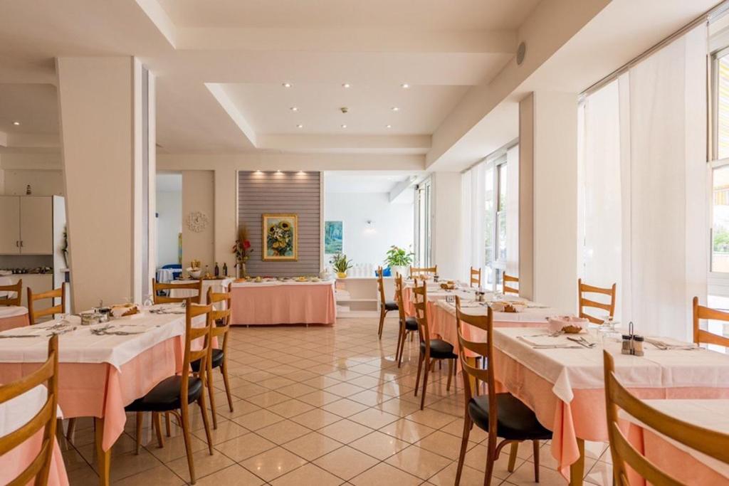 jadalnia ze stołami i krzesłami oraz kuchnia w obiekcie Hotel Alda w mieście Cervia