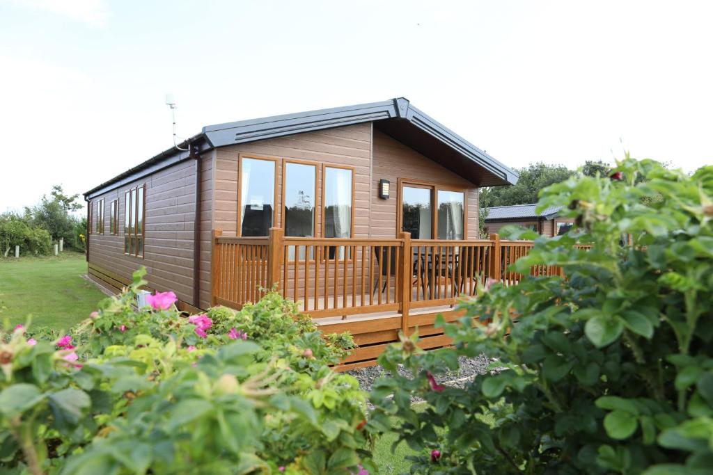 a small cabin with a deck in a garden at Cosy Dreams Lodge in Beal