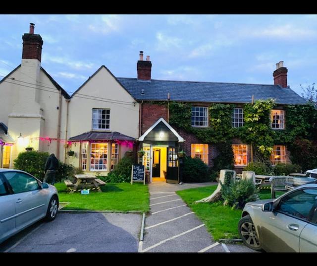 una casa grande con coches estacionados frente a ella en The Compasses Inn, en Fordingbridge