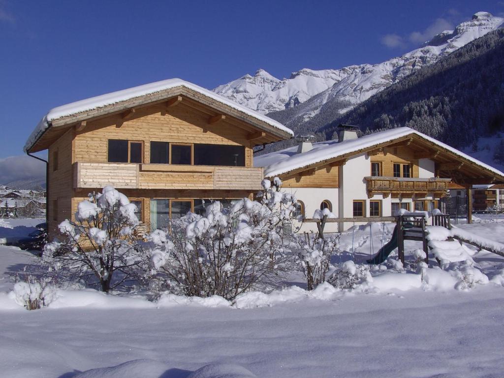una casa di tronchi nella neve con le montagne di Bioholzhaus Haslinger a Neustift im Stubaital
