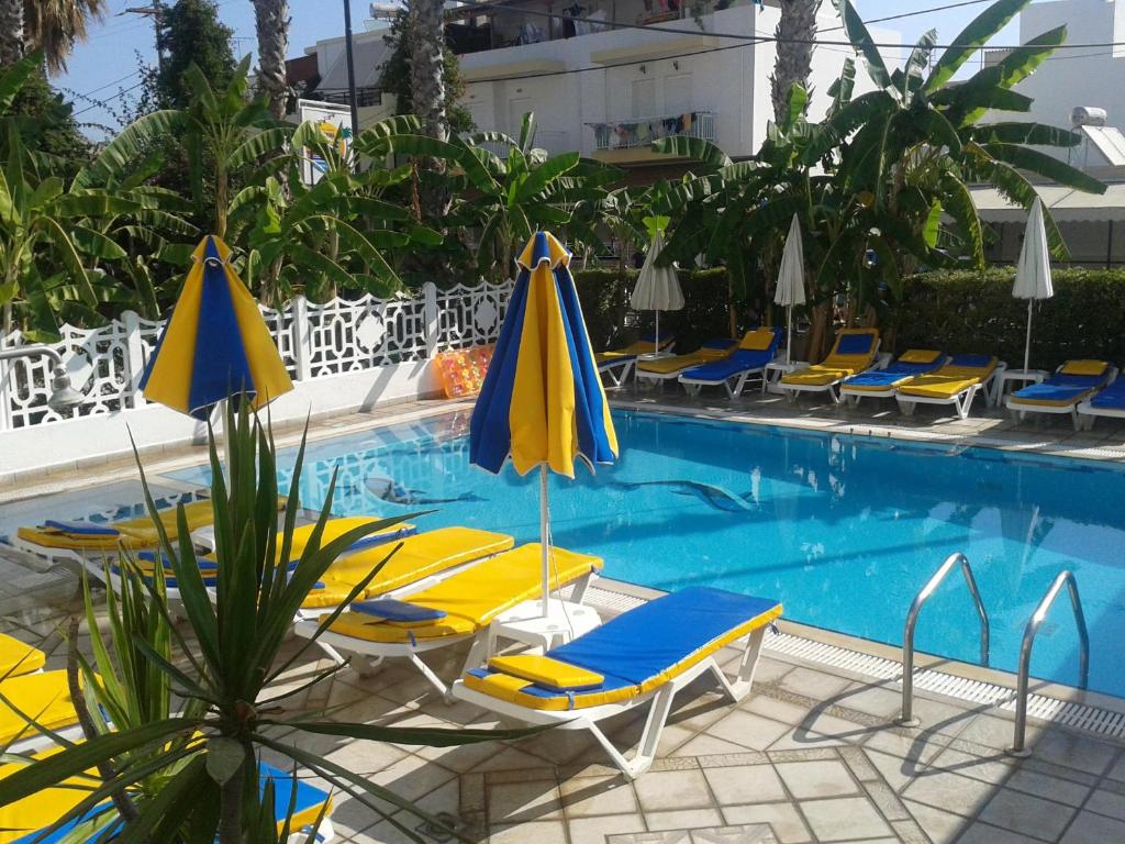 a swimming pool with lounge chairs and umbrellas at Elite Apartments in Kos