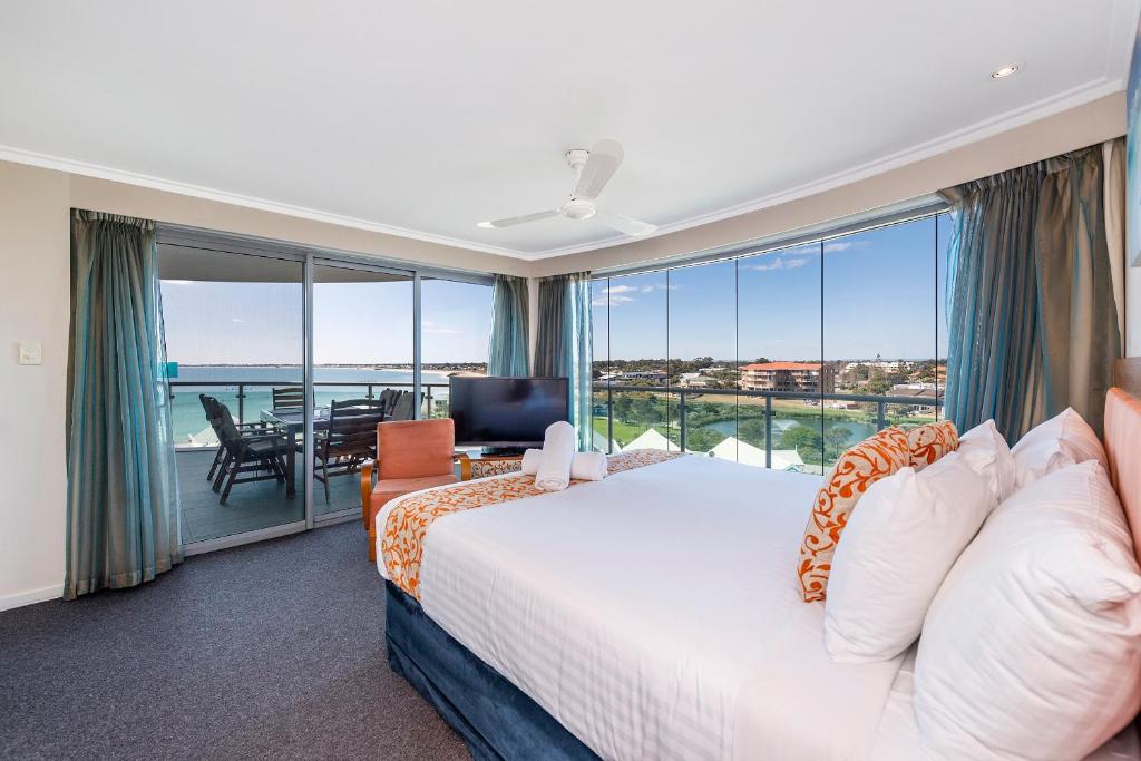 A 406 FANTASTIC OCEAN BEACH and MARINA VIEW APT - MANDURAH في ماندورا: غرفة نوم مع سرير وإطلالة على المحيط