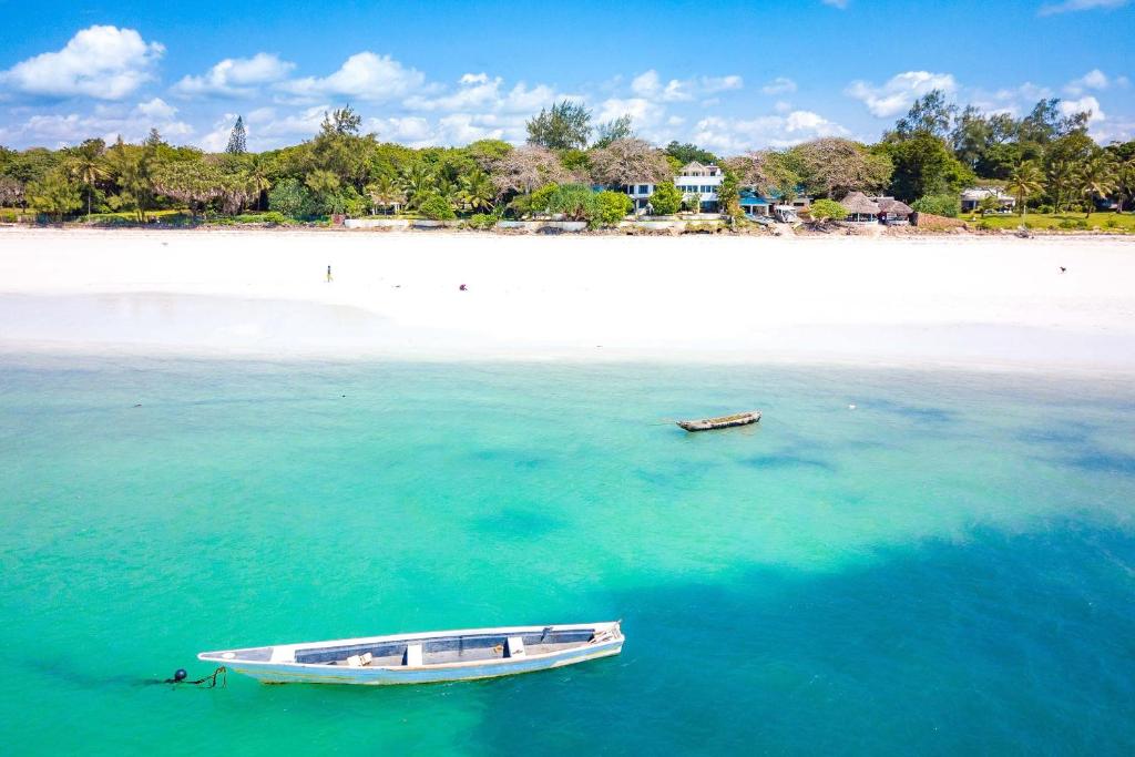 un barco sentado en el agua junto a una playa en Tequila Sunrise Forest Cabana - on Diani Beach en Diani Beach