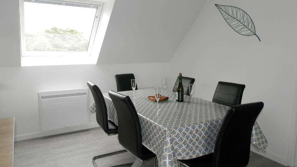 a dining room with a table and black chairs at Location Tromeal Lasalle in Saint-Pol-de-Léon