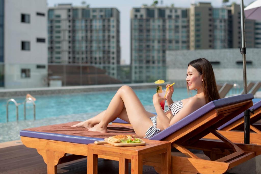 A poolside lounging scene with a guest dining on a sun lounger.