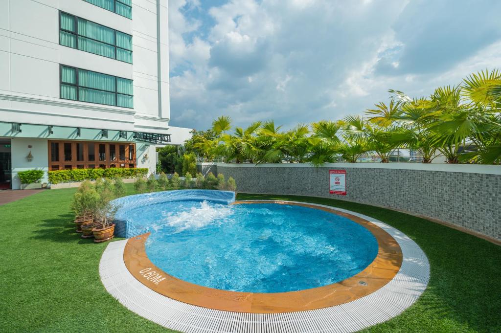 A compact outdoor pool beside the hotel building and landscaped grounds.