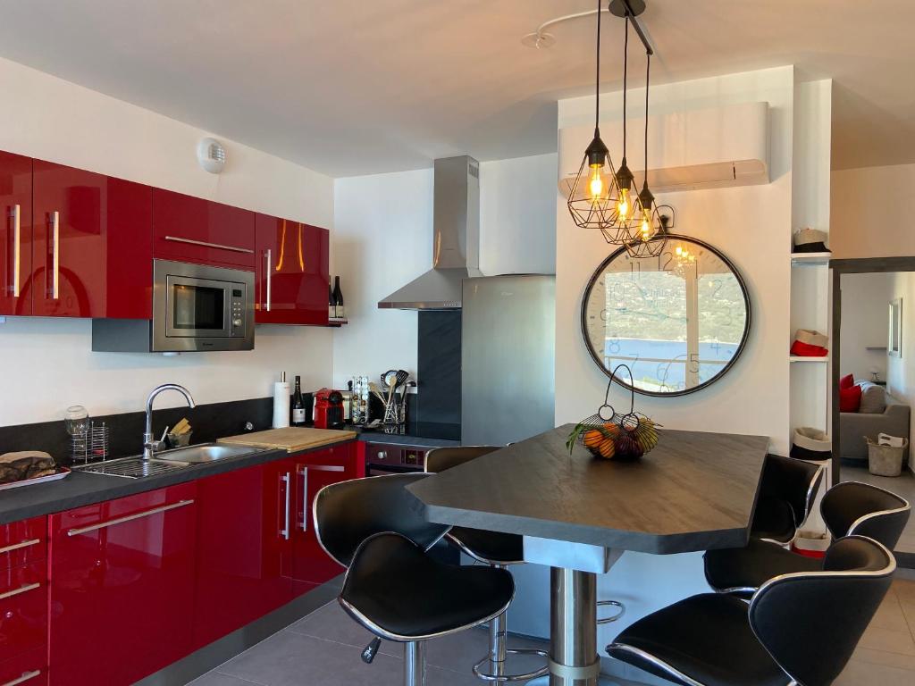 a kitchen with red cabinets and a table with chairs at Appartement neuf tout confort en bord de mer in Propriano