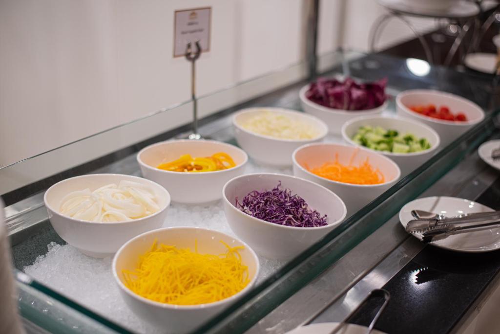 Bowls of shredded vegetables and salad ingredients on ice.
