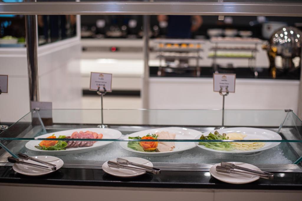 Plated cold breakfast items arranged behind a glass buffet guard.