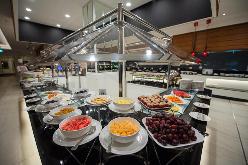 A long self-service buffet with fruit, cold dishes, and serving ware.