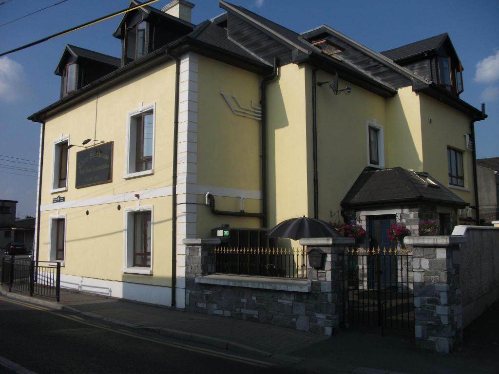 a yellow house on a street with a fence at Clare Street B&B in Nenagh