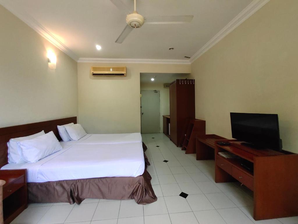 a hotel room with a bed and a flat screen tv at Wawa's Golf View Inn in Taiping