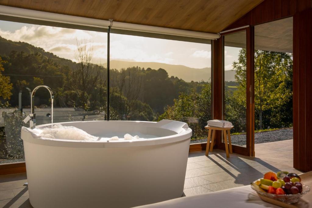 a bath tub in a room with a large window at Cabañas Deluxe Basajaun Basoa by IrriSarri Land in Igantzi