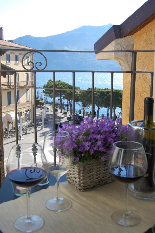 two glasses of wine sitting on a balcony with flowers at Casa del lago in Menaggio