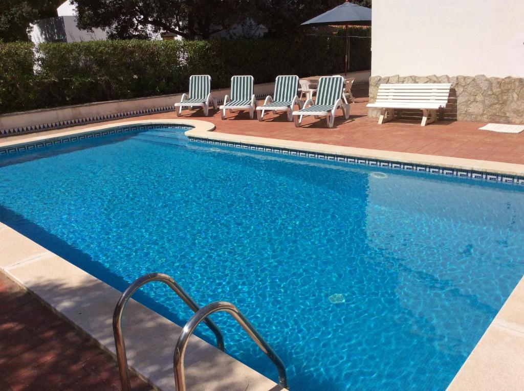 una piscina con tumbonas junto a en VILLA NUEVA en Cala Galdana