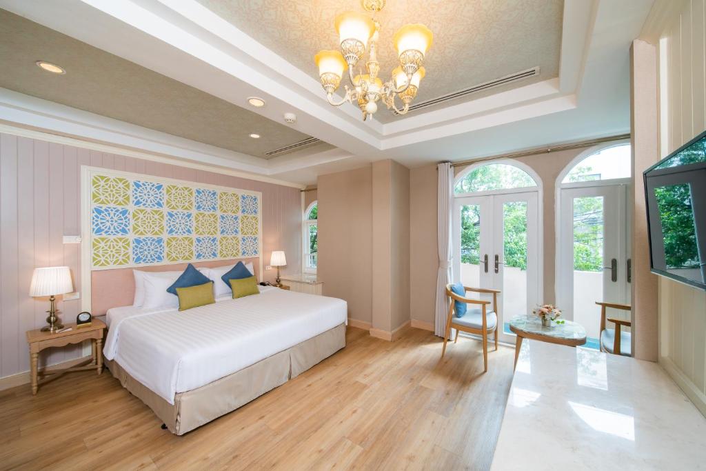a bedroom with a white bed and a chandelier at La Petite Salil Sukhumvit 8 in Bangkok