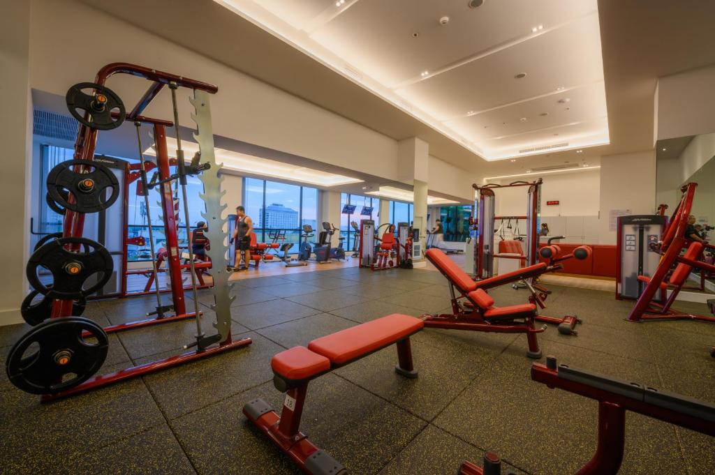 A large fitness room combines free weights, benches and red resistance machines.
