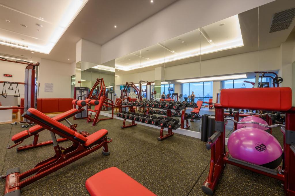 A spacious weight-training room is fitted with red machines and a long mirrored wall.