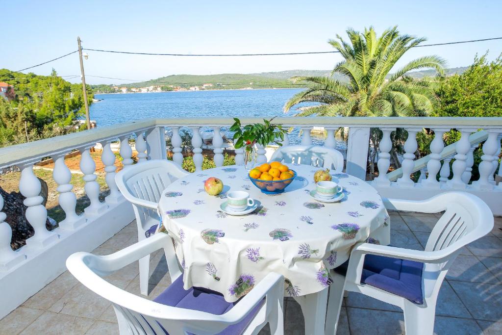 einen Tisch und Stühle auf einem Balkon mit Meerblick in der Unterkunft Apartments Kolic in Veli Rat