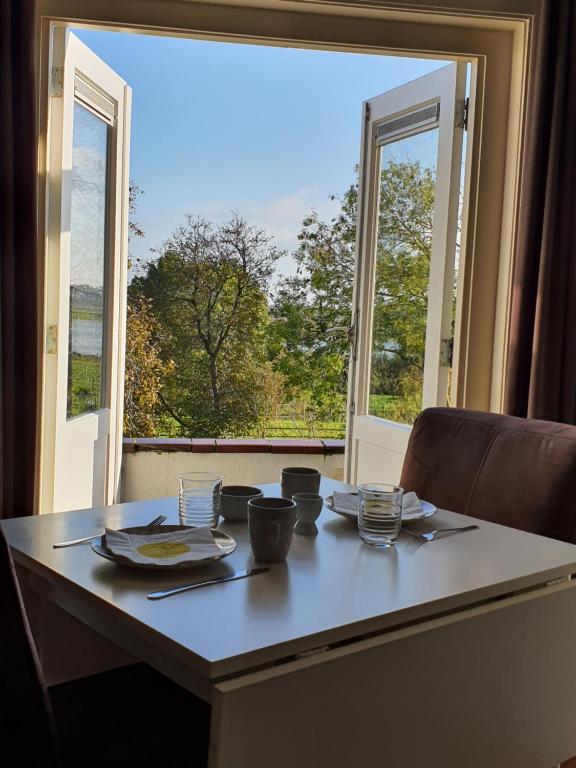 stół z talerzami i miskami przed oknem w obiekcie B&B MaasLandje w mieście Wijk en Aalburg