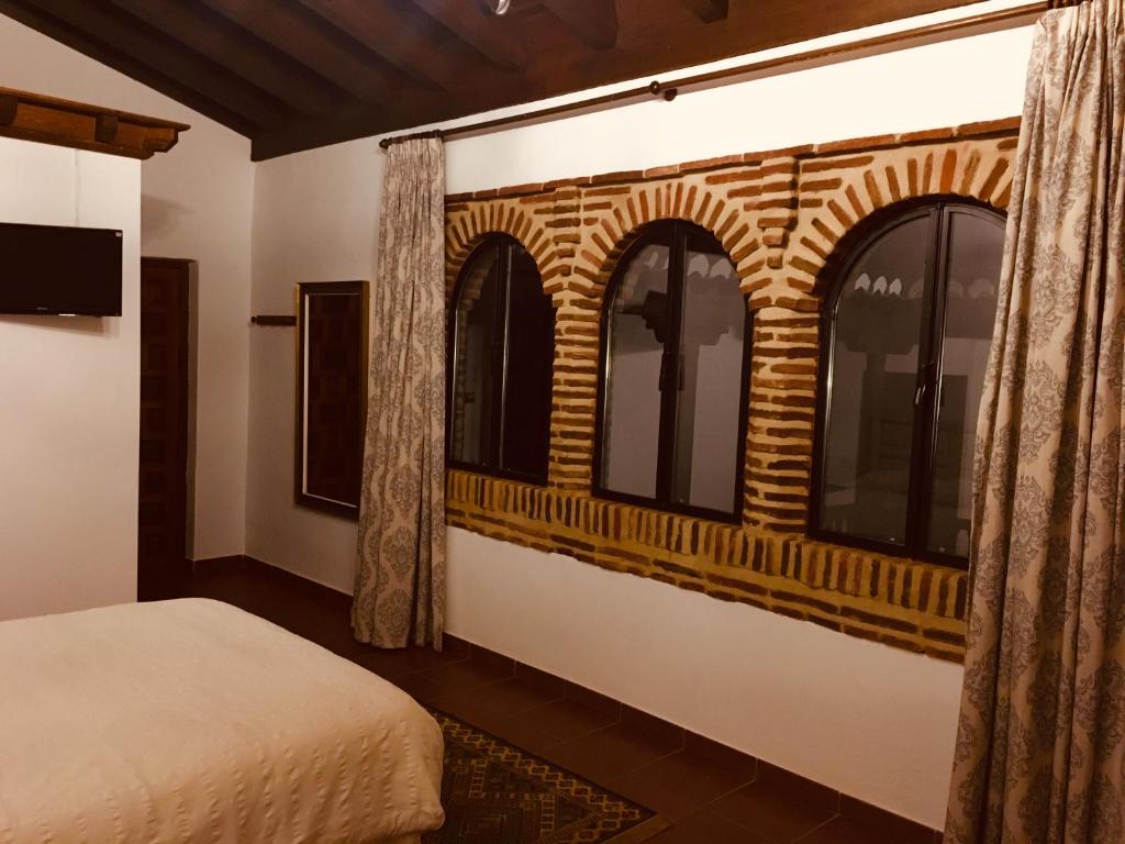 1 dormitorio con una pared de ladrillo y ventanas en HABITACIONES LAS TERMAS, en Guadix