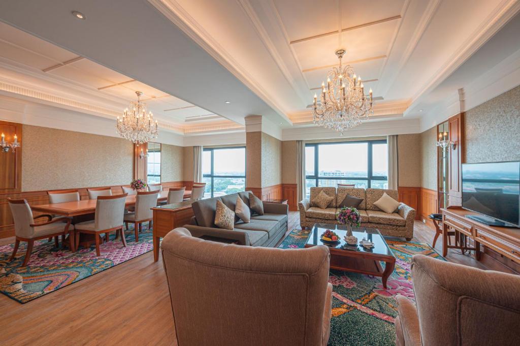 A formal suite living room with sofas, armchairs, dining furniture, and broad city-facing windows.