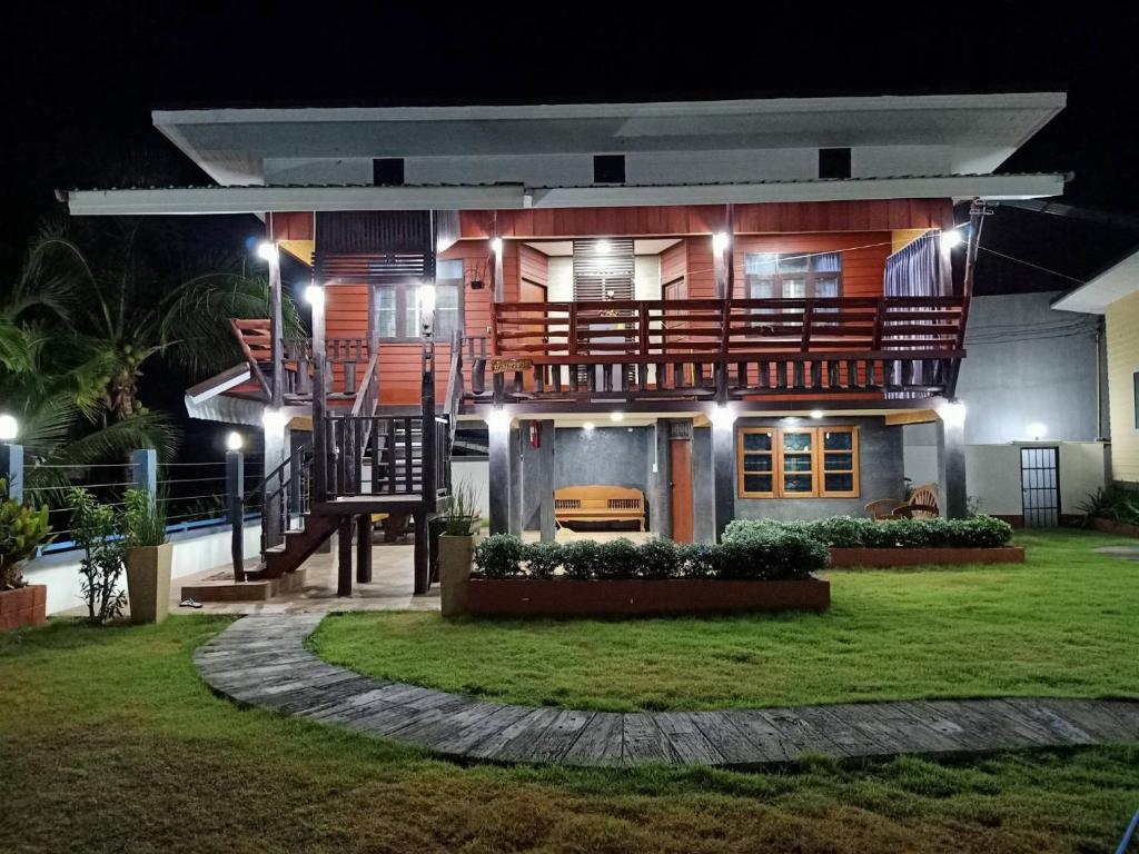 une grande maison avec une grande terrasse la nuit dans l'établissement บ้านสวนแก้วเฮือนคำ, à San Pa Tong