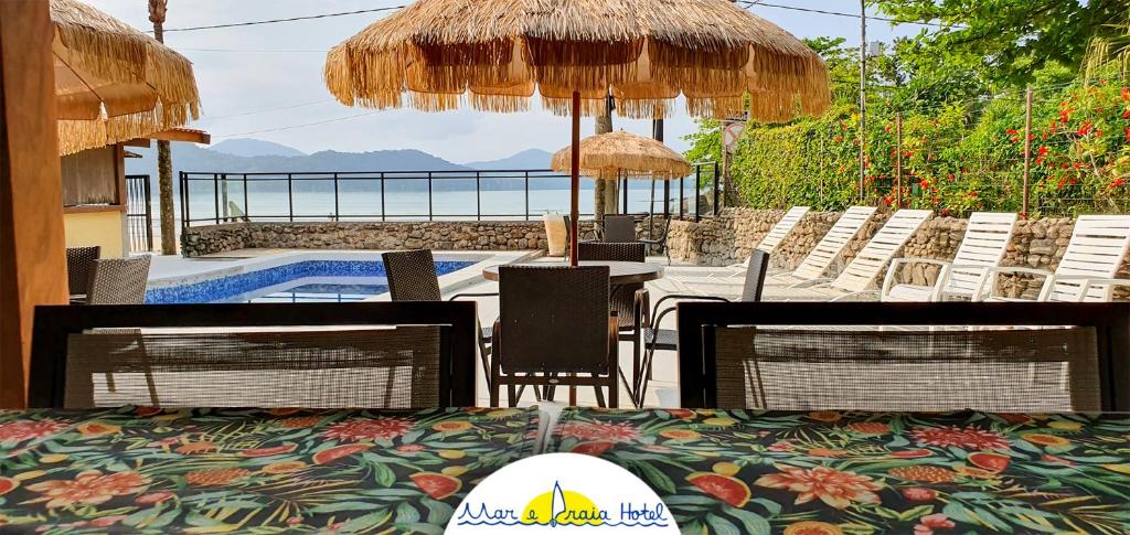 a patio with a table and chairs and a swimming pool at Mar e Praia Hotel in Ubatuba