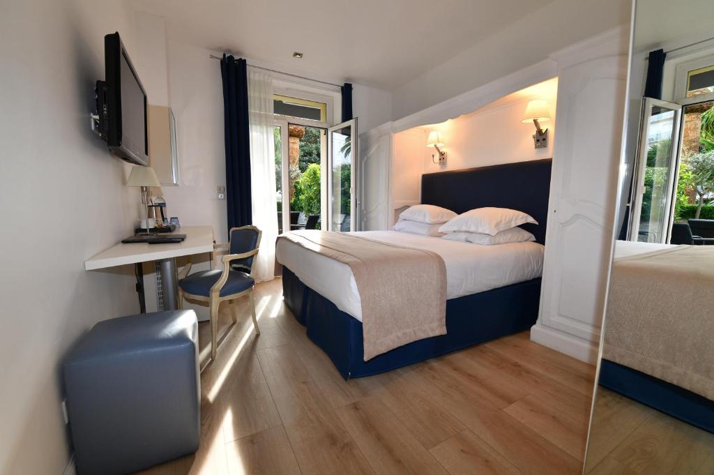 فندق دو بروفانس في كان: غرفة نوم بسرير ومكتب ومرآة
