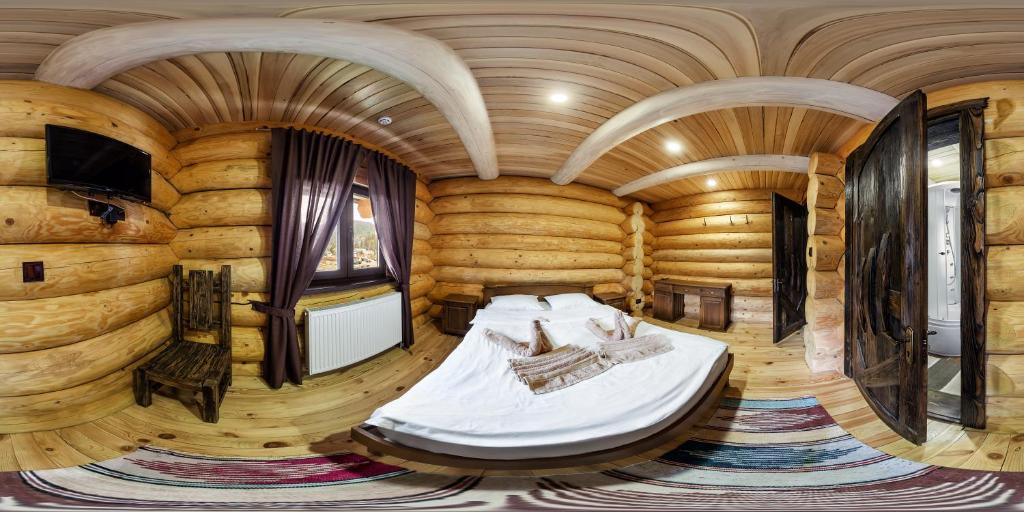 una camera da letto in una baita di tronchi con un letto in esso di Berloga Pylypets a Pilipets