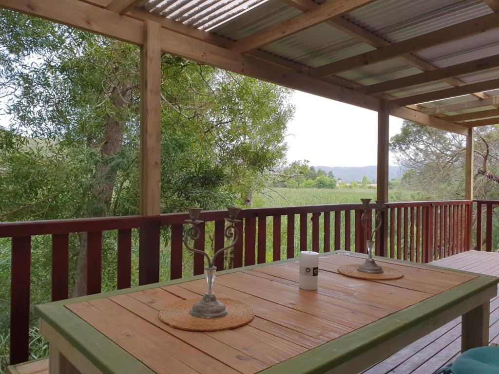 a wooden table on a deck with a coffee cup on it at WOODPECKER in Plettenberg Bay