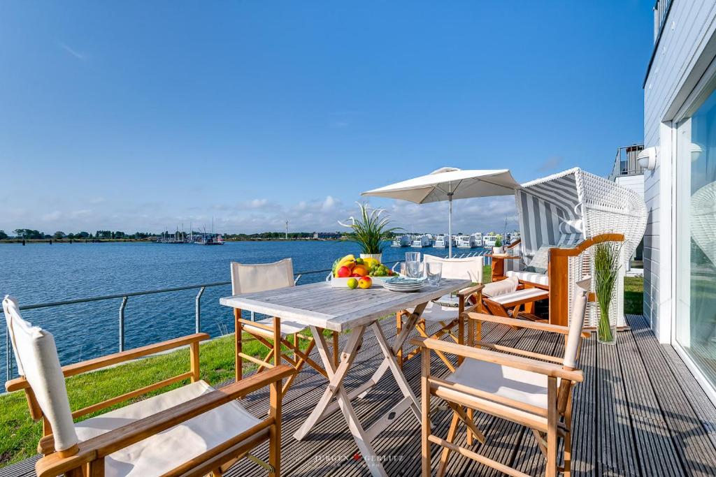 un tavolo e sedie su una terrazza con vista sull'acqua di Ferienwohnung Pier 51 a Olpenitz