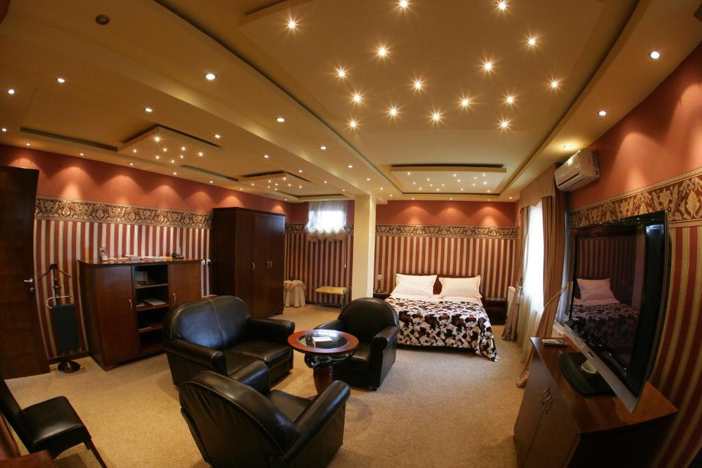 une chambre d'hôtel avec un lit, des chaises et une télévision dans l'établissement Garni Hotel Garson-Lux NS, à Novi Sad