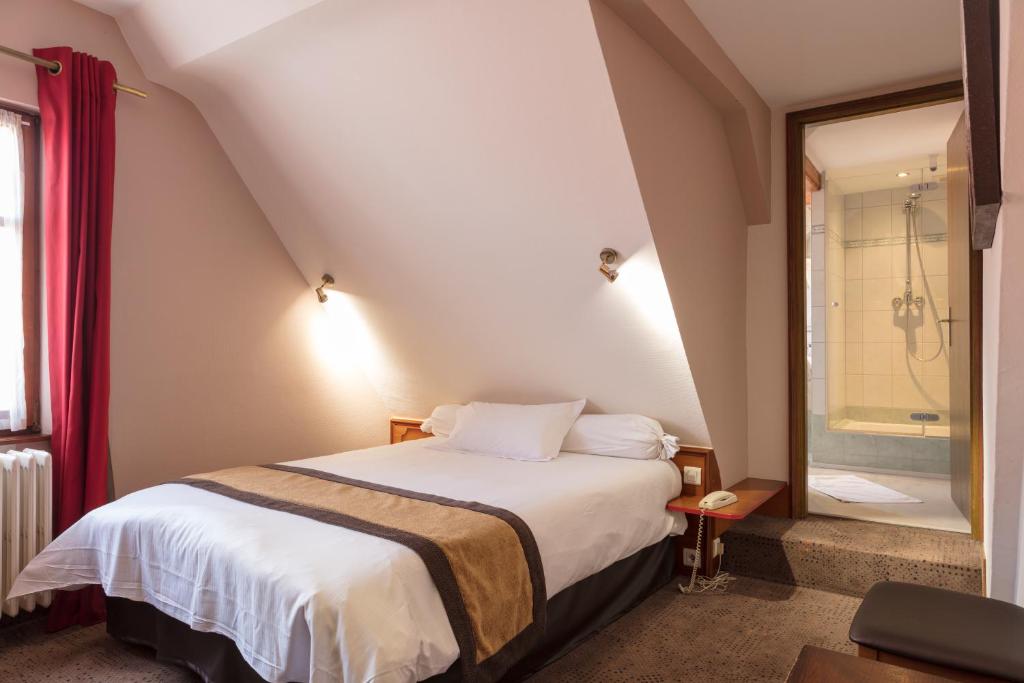 a bedroom with a bed and a bathroom with a shower at Logis Hotel Restaurant A L'Etoile in Mittelhausen